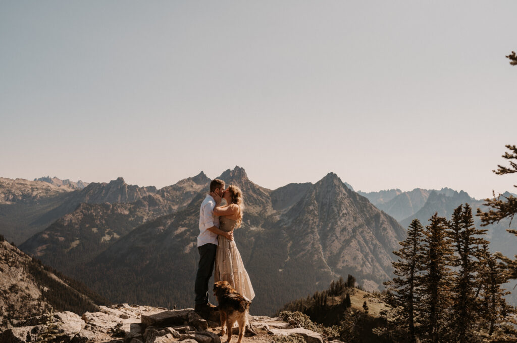 couple embraces in front of mountain peaks after surprise proposal near North Cascade National Park