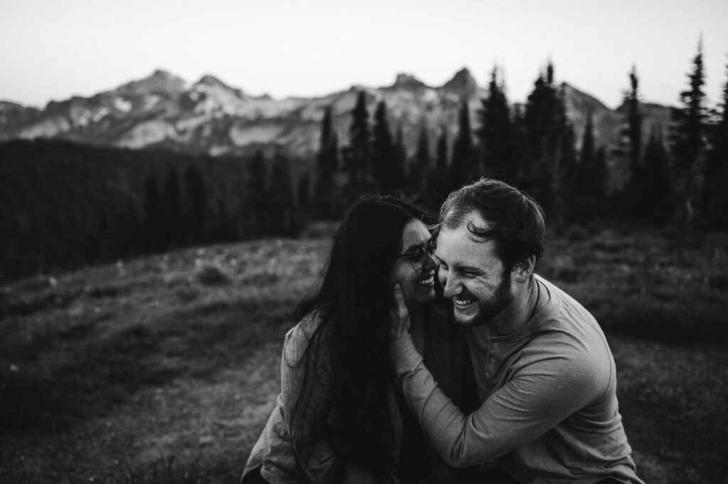 couple laughing during engagement photos with view of tatoosh range