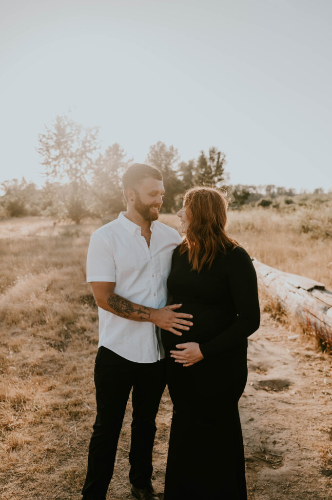 husband and wife look at each other during golden hour photoshoot