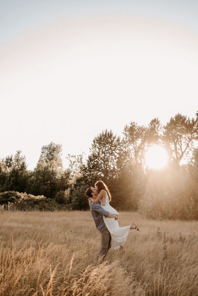 couple dances in golden hour field for engagement session 