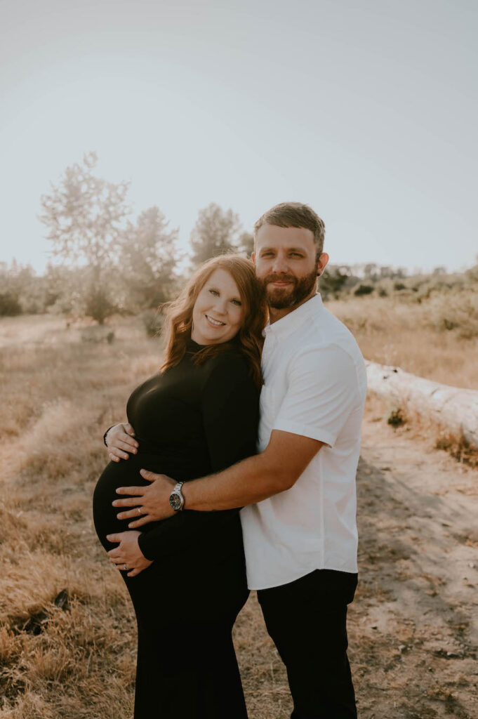 Husband and wife hug during maternity session 