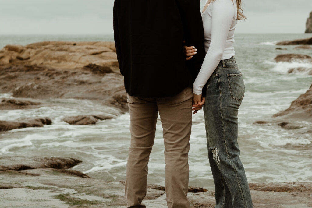 couple standing in front of the ocean during their oregon coast engagement session