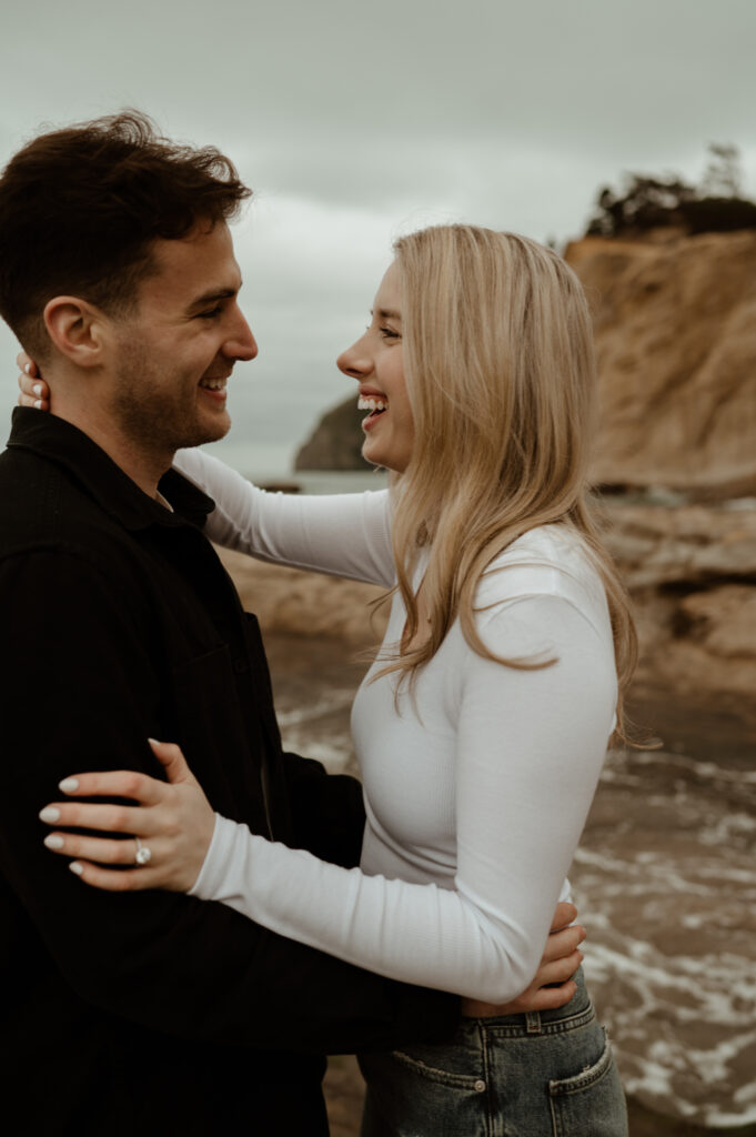 couple laughing during their oregon coast engagement session in Pacific City