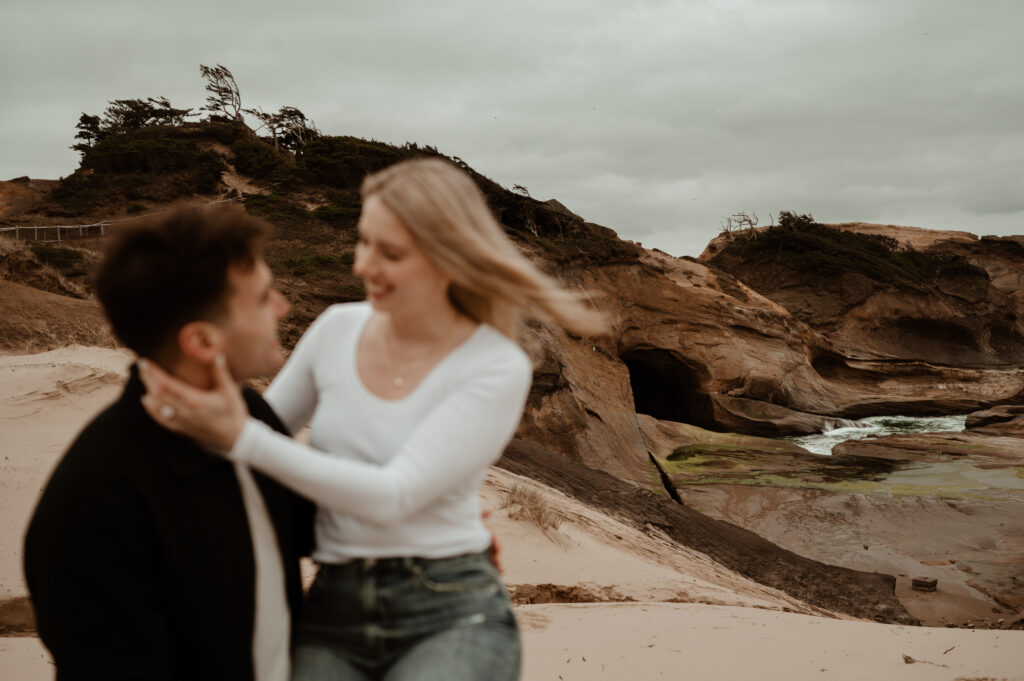 couple looking at each other on sand dune at cape kiwanda state natural area