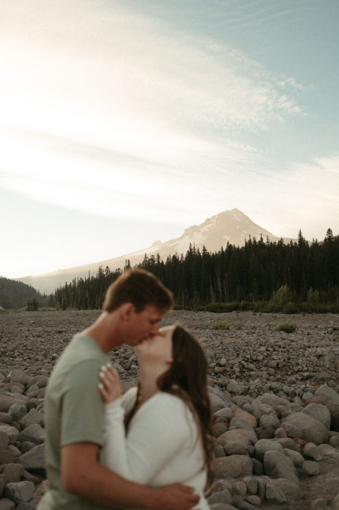 mount hood behind couple kissing during their mountain engagement