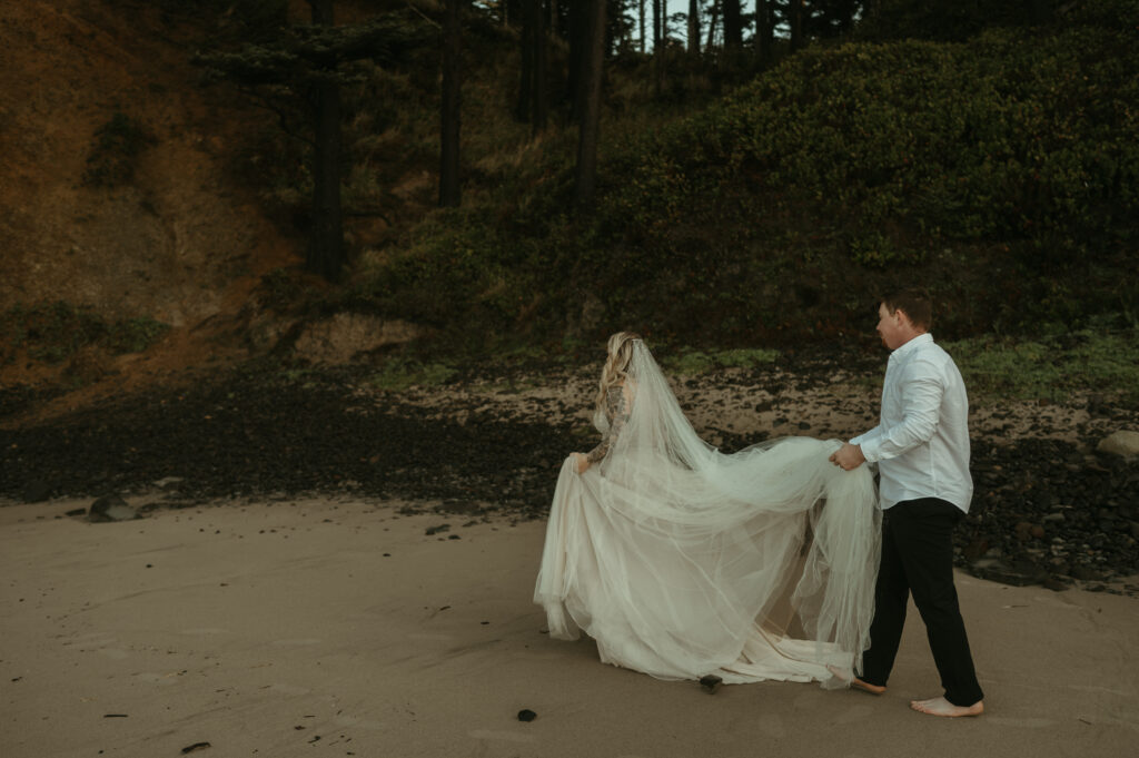 Groom holds brides dress during Oregon Coast elopement