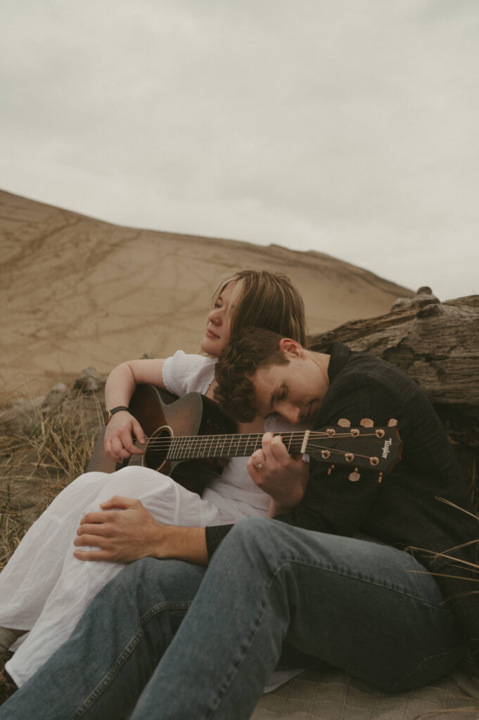 couple playing music during oregon coast engagement session