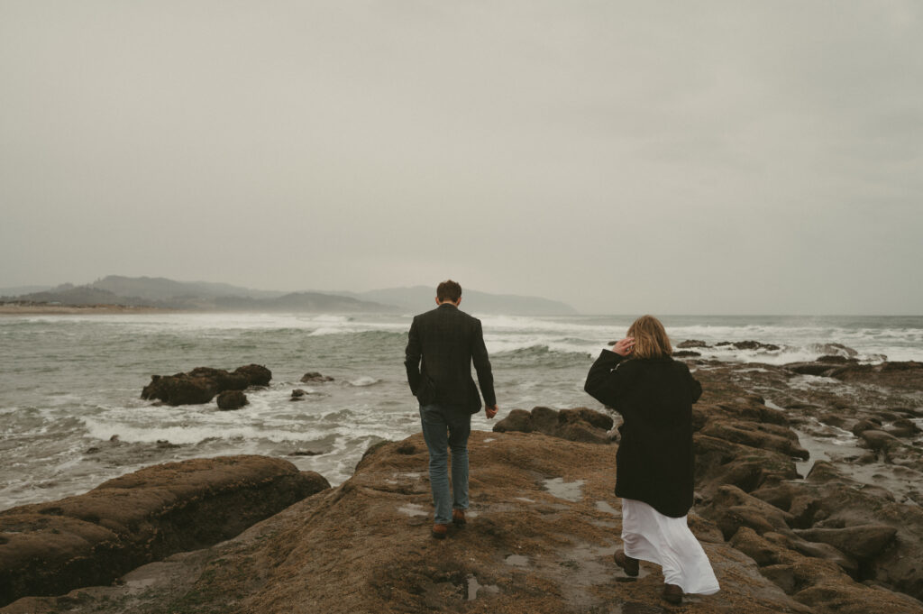 couple walking on rocks at cape kiwanda