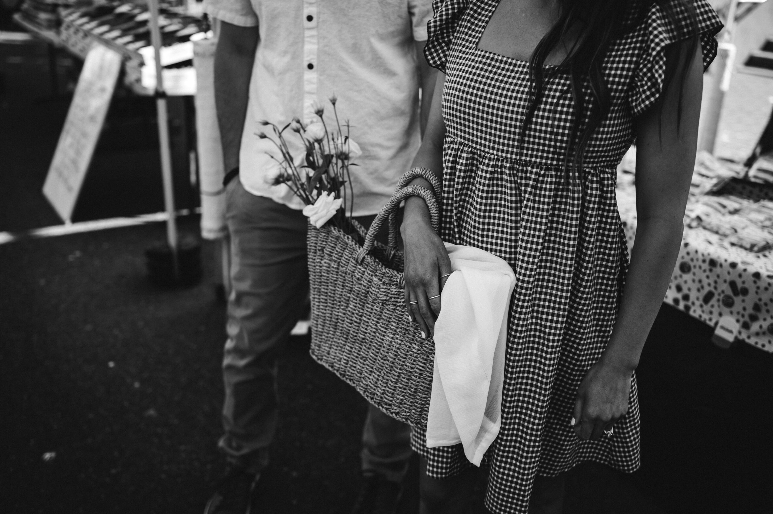 woman holds basket of flowers at Tacoma Farmers Market in July