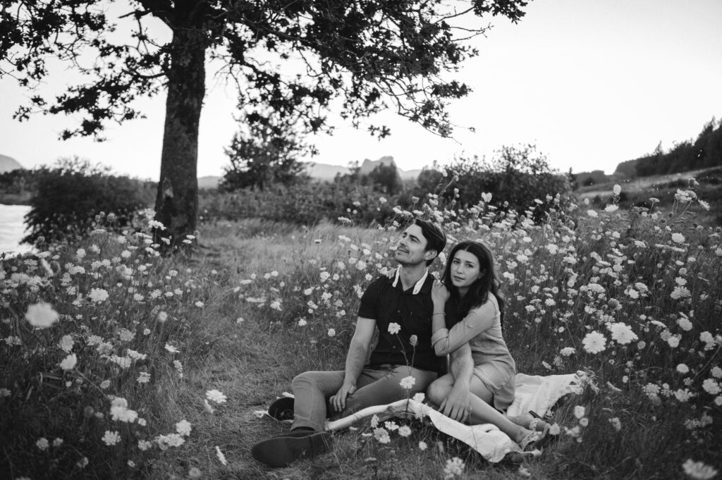 couple sits in field of white wildflowers 