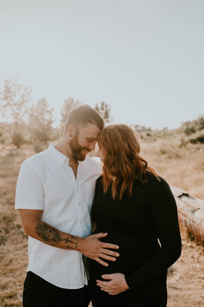 husband and wife laugh and smile during maternity session in Salem, Oregon