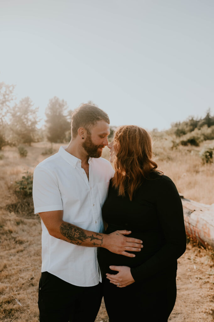 husband and wife tickle noses during maternity session