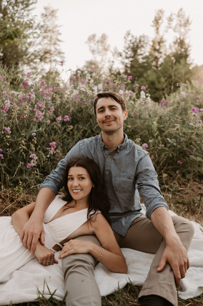 couple sitting together in front of pink wildflowers