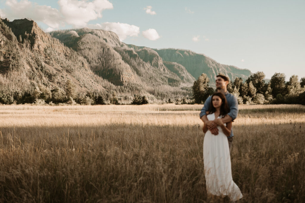 couple stands in field in columbia river gorge for engagement session