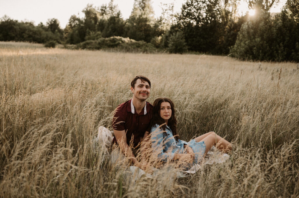 Couple sits in field during sunset columbia river gorge engagement session