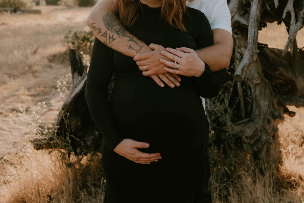 holding hands on pregnant belly during sunset maternity session