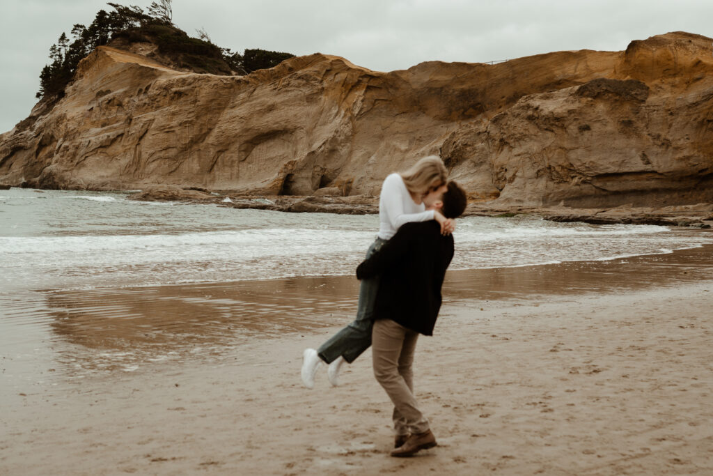 couple dancing on the beach in front of cape kiwanda nature reserve in pacific city during an oregon coast engagement session