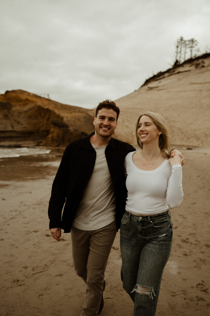 couple walking on the beach at cape kiwanda in pacific city